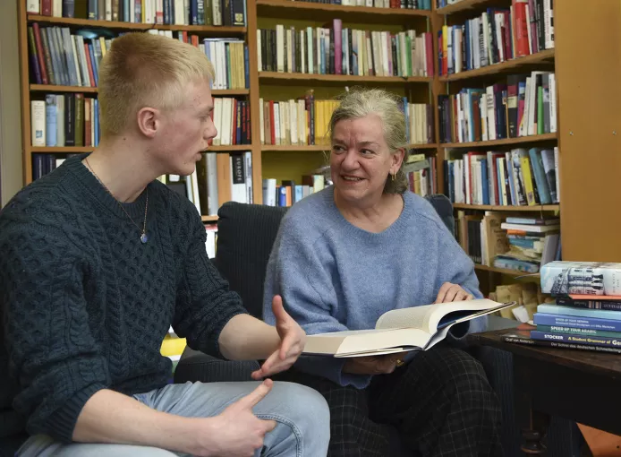 Academic sitting with student discussing a text book